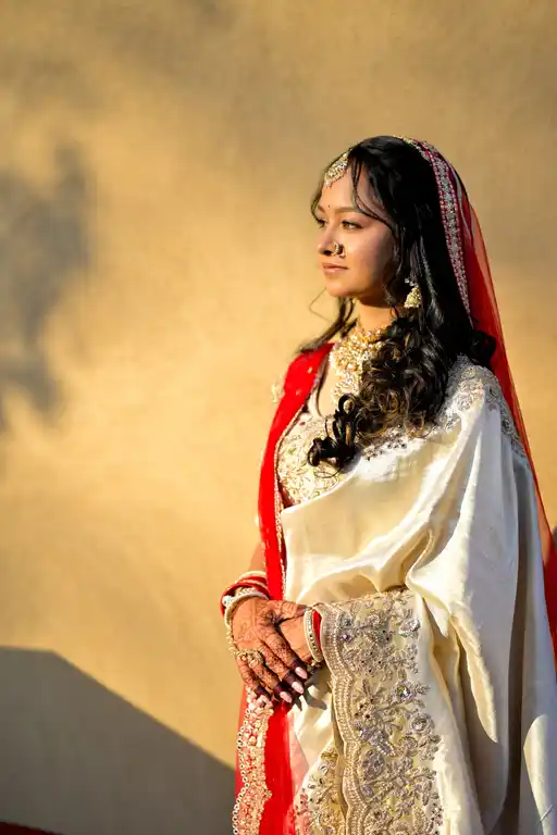 Bride in a red dupatta and ivory saree in golden hour light