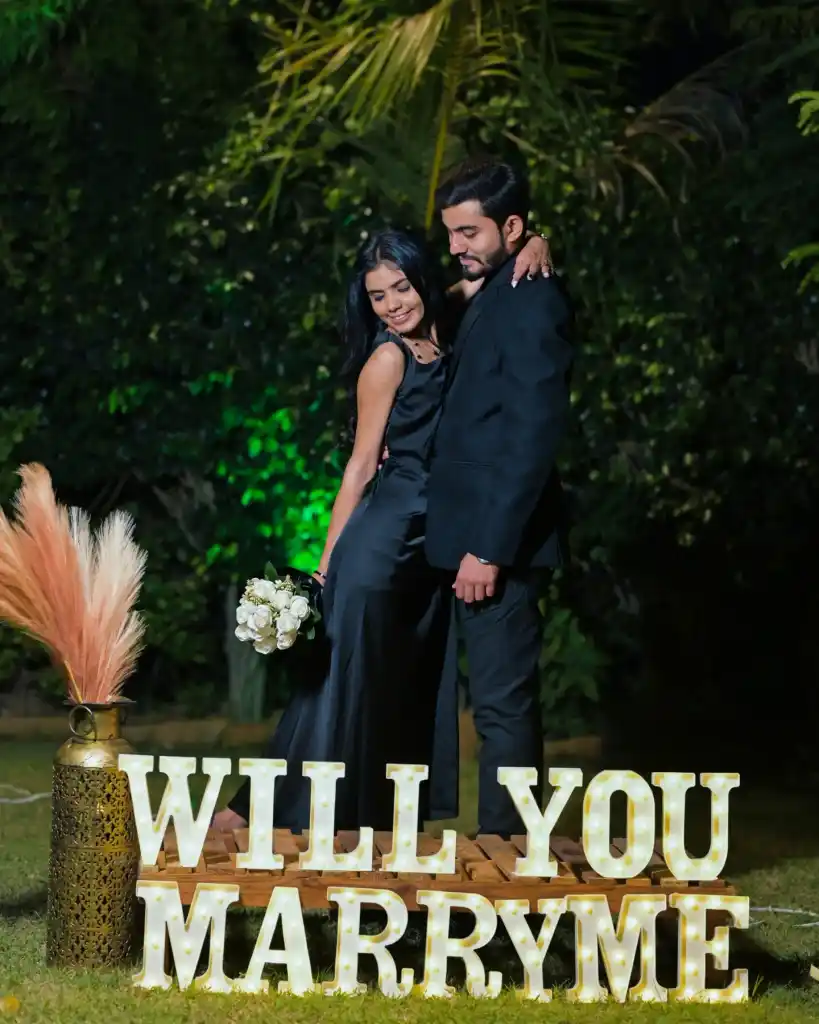 Night proposal with a lit Will You Marry Me sign
