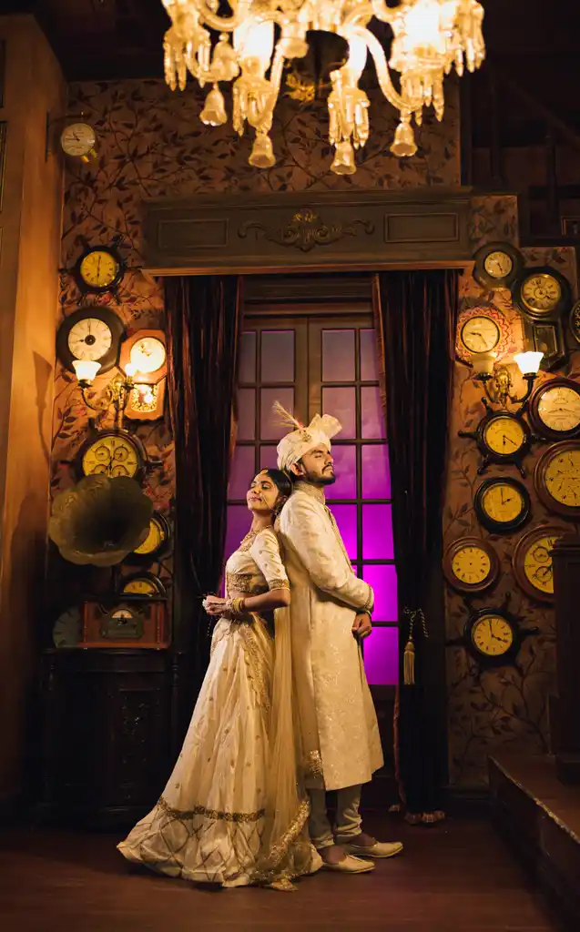 Couple back to back under a chandelier in a vintage clock room