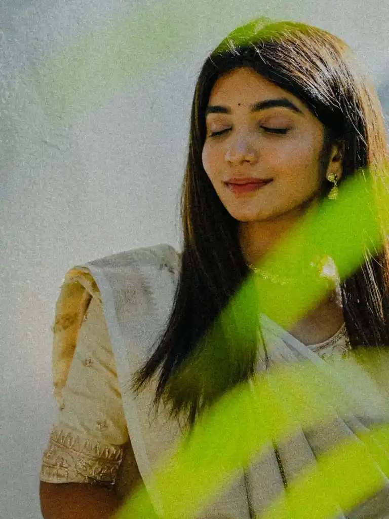 Bride with eyes closed as green haldi colour sweeps past