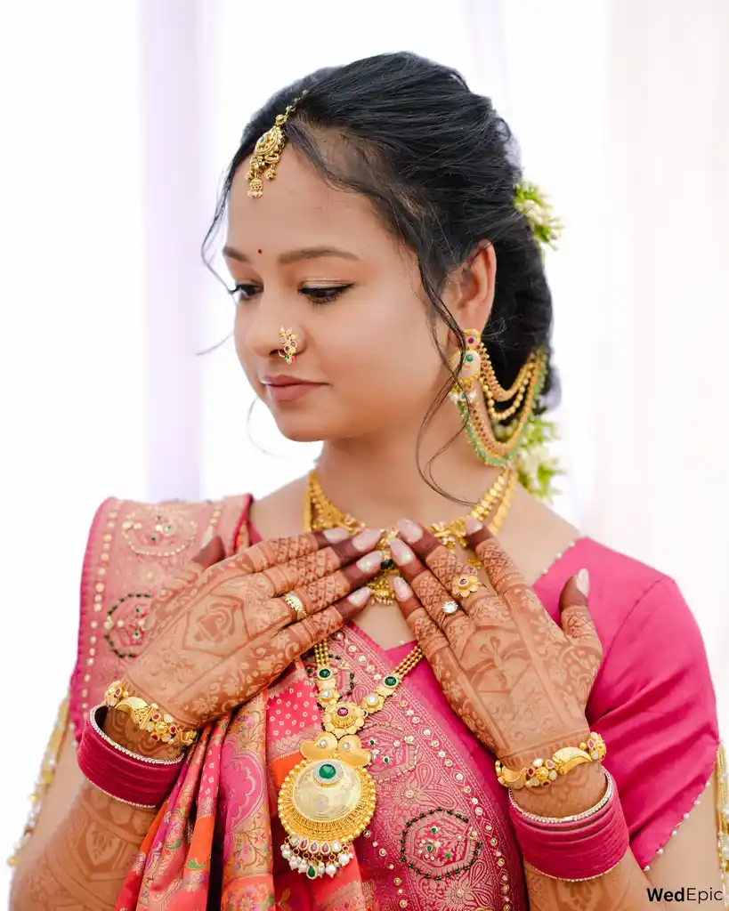 Bride in a pink saree with gold jewellery and detailed mehendi