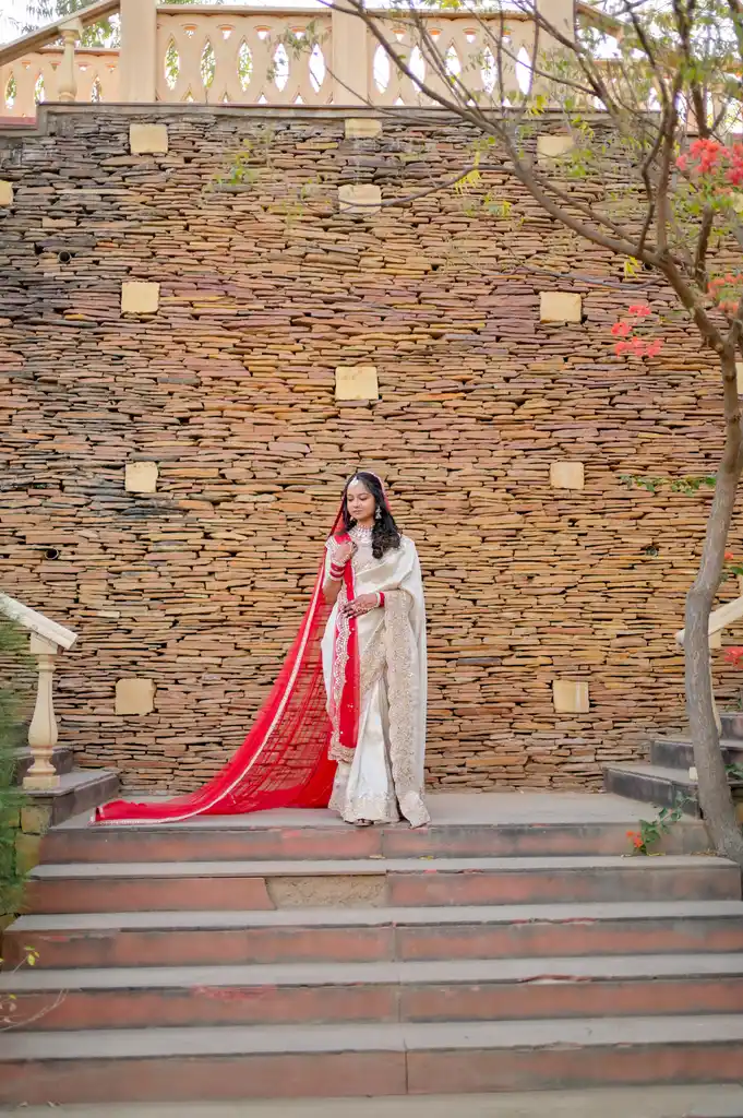 Bride on stone steps with a long red trail